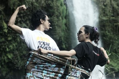 Side view of man and woman standing against plants