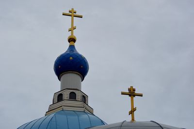 Low angle view of cross by building against sky