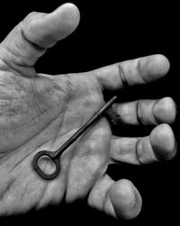 Close-up of hand holding eyeglasses against black background