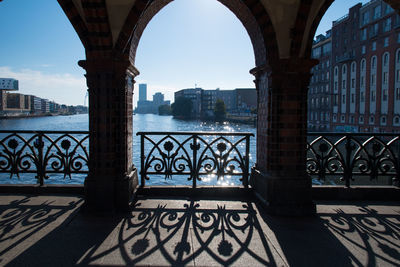 Bridge over river in front of buildings against clear blue sky