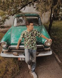Young man standing by vintage car