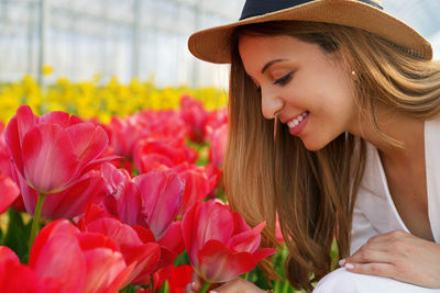 Happy beauty girl with straw hat smelling blooming tulips on farm ready to be harvested