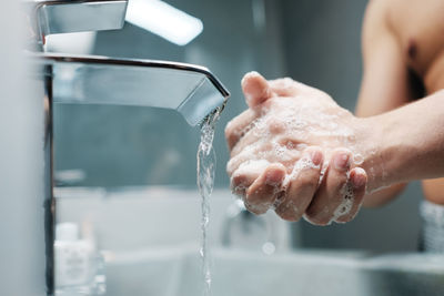 Midsection of man holding water in bathroom