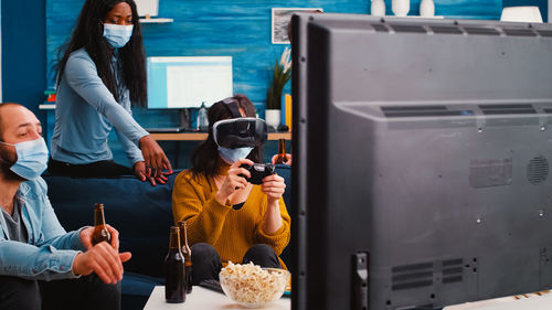 Cheerful people playing video game while wearing mask