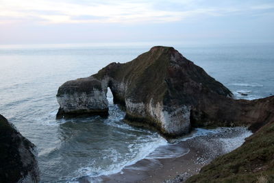 Rock formation on sea shore against sky