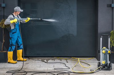 Mature man cleaning garage shutter outdoors