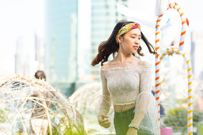 Young woman looking away while standing outdoors