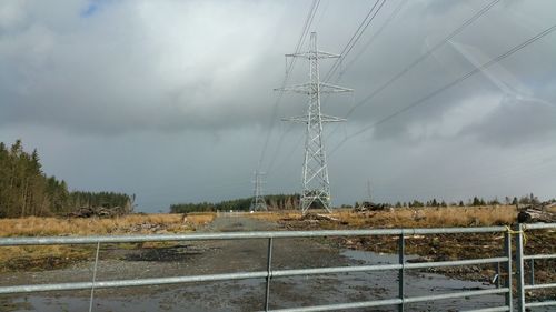 Electricity pylon against cloudy sky