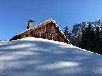 Low angle view of snowcapped mountains against clear blue sky