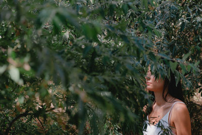 Side view of woman standing amidst plants