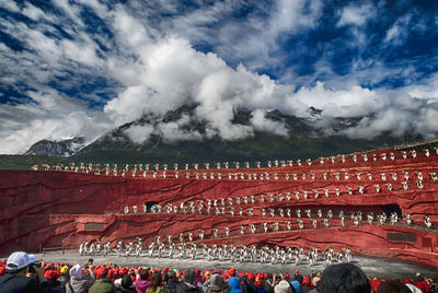 Group of people on mountain against cloudy sky