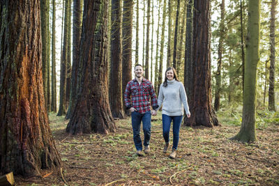 Attractive trendy couple walking through forest, looking ahead.