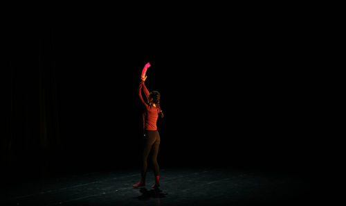 Rear view of woman standing against black background