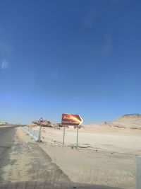 Lifeguard hut on desert land against clear blue sky