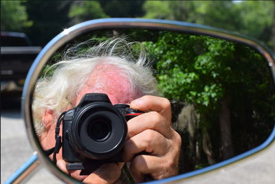Reflection of person photographing on side-view mirror