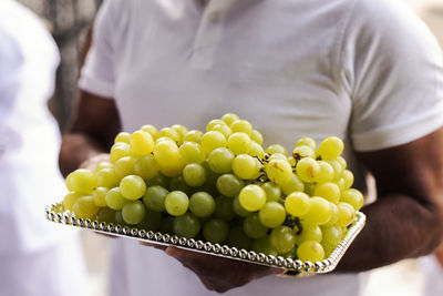 Man holding plate of green grapes