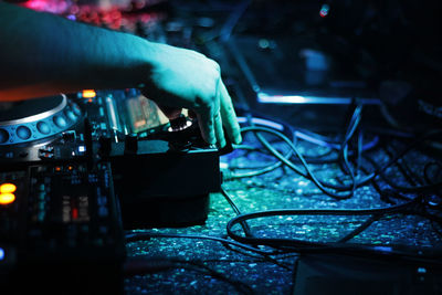 Cropped hand of man using sound mixer at night