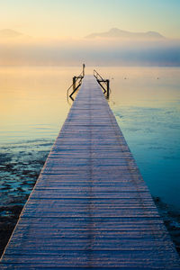 Pier over sea against sky during sunset