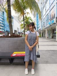 Portrait of young woman standing against built structures