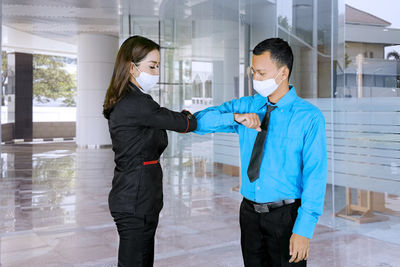 Businesswoman doing elbow bump with businessman while standing in building