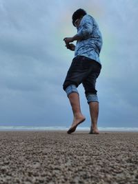 Side view of man on beach against sky