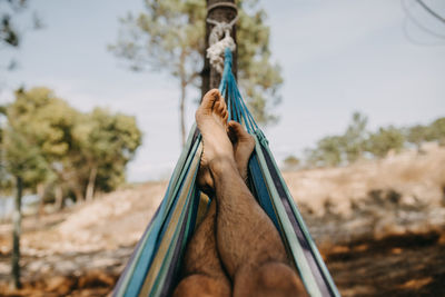 Low section of man hanging on rope against trees