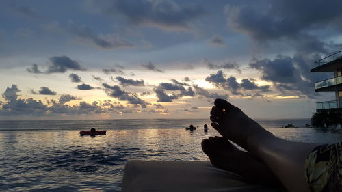 Person on sea against sky during sunset