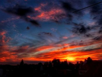 Low angle view of silhouette houses against dramatic sky