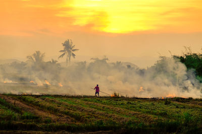 Man standing on field against sky during sunset