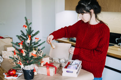 Rear view of woman sitting on table at home
