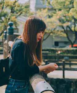 Woman standing by railing against trees