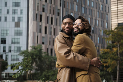 Gay couple embracing each other in front of building exterior