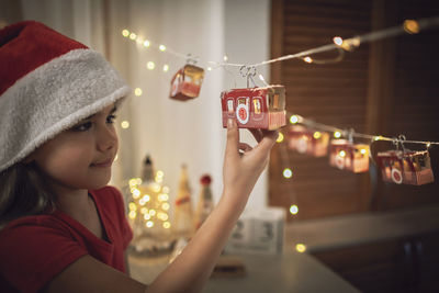 Close-up of girl touching christmas decoration at home