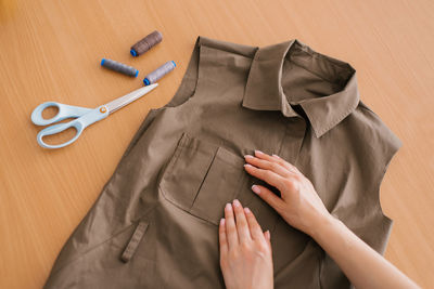 Top view of a dressmaker working on sewing a shirt on a table with threads and scissors
