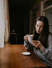 Young woman using mobile phone while sitting at home