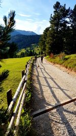 People walking on road by mountain against sky