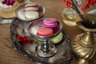 Multi-colored macaroons on an old silver dish, on the table.