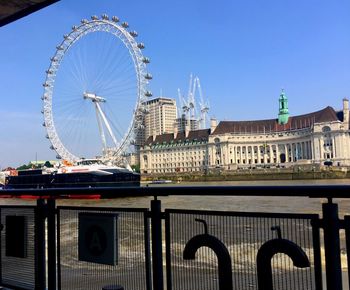 Ferris wheel in city against clear blue sky