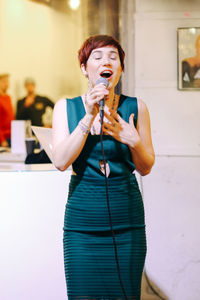 Young woman drinking water from glass while standing on floor