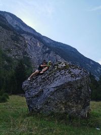 Man standing on rock by land against sky