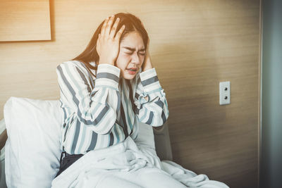 Teenage girl sitting on bed at home