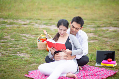 Young couple holding smart phone while sitting on grass