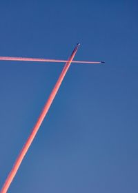 Low angle view of airplane flying against clear blue sky