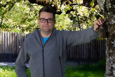 Portrait of mid adult man standing by tree at park