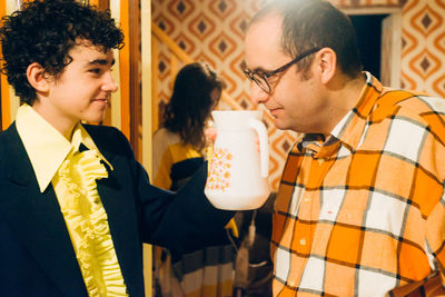 Father smelling jug held by son at home