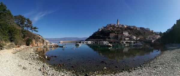 Panoramic view of lake and buildings against blue sky