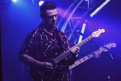 Man playing guitar while standing on stage