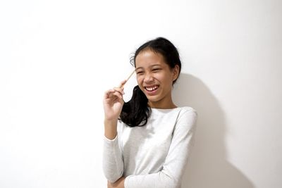 Smiling young woman standing against white background