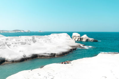 Scenic view of white milos beach against clear blue sky