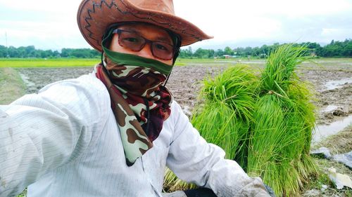 Portrait of farmer in hat and scarf on field